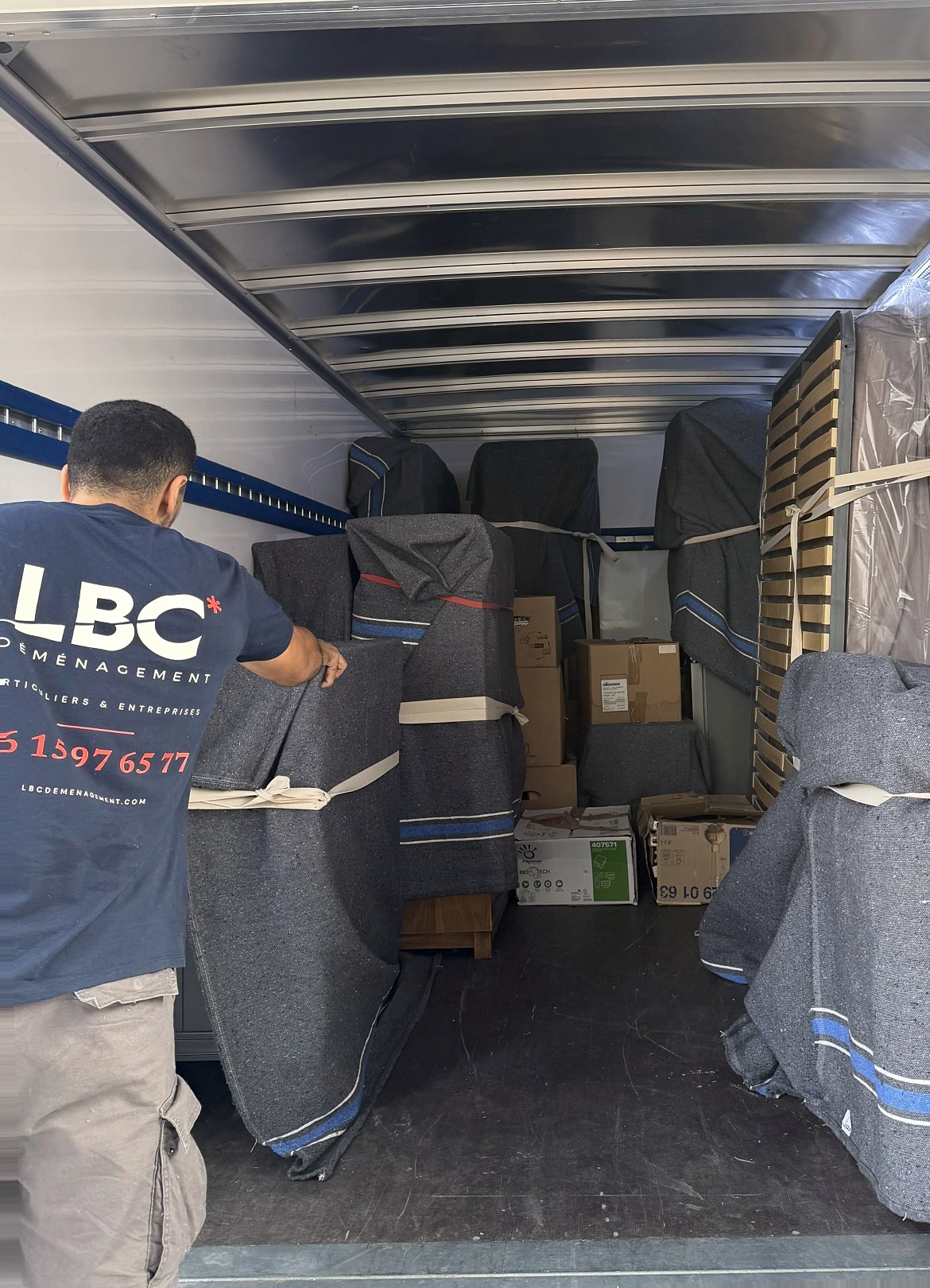 Un déménageur LBC Déménagement charge le camion : les meubles sont sous couvertures matelassées et sanglés